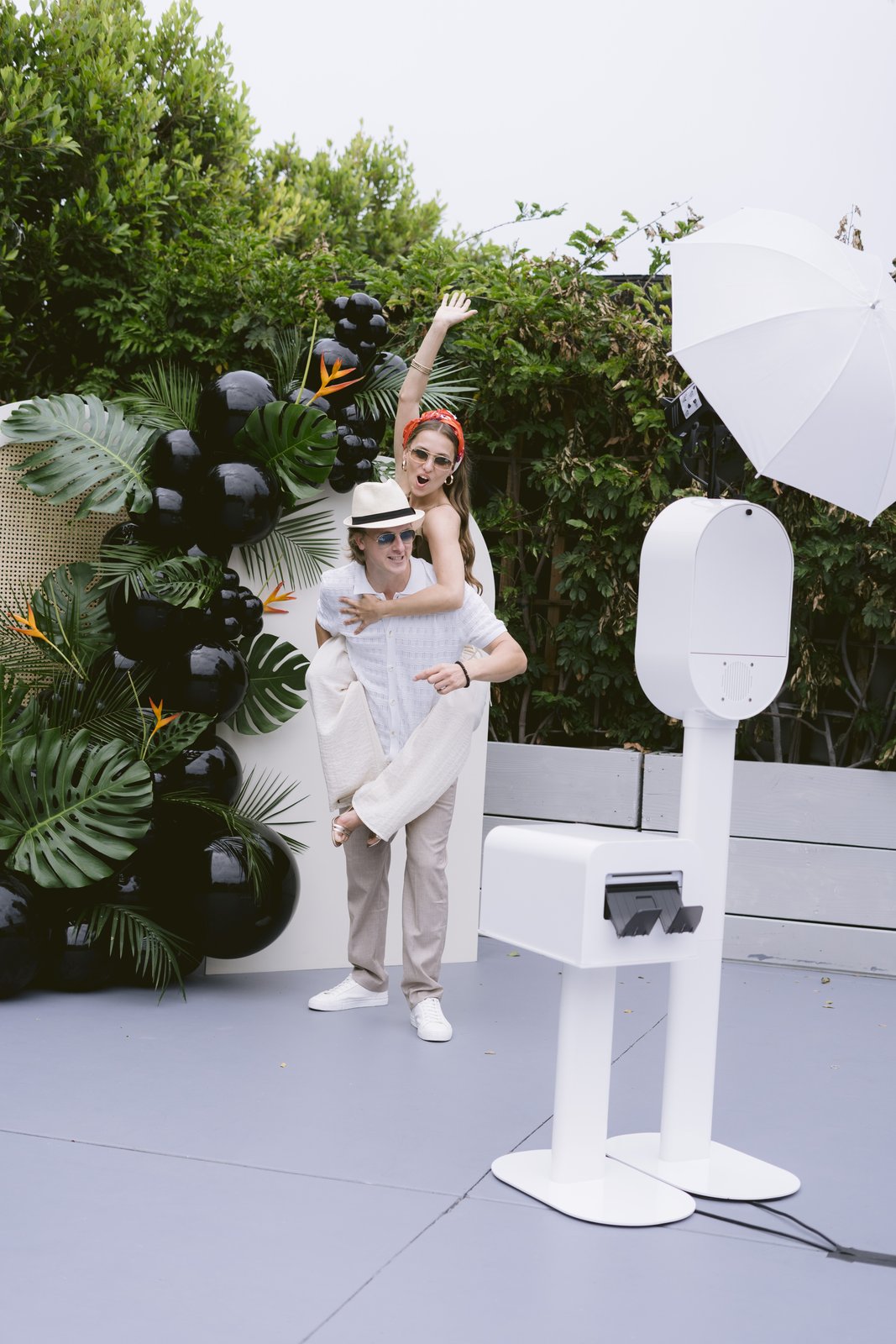 Couple laughing mid-jump for a piggyback photo at a garden party